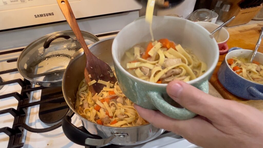 made from scratch chicken noodle soup being ladled into a bowl